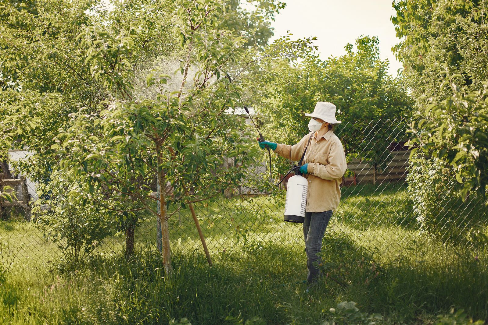 A Lava Rock Pest Control technician in protective gear treating the perimeter of a Santa Clara, Utah home with a sprayer