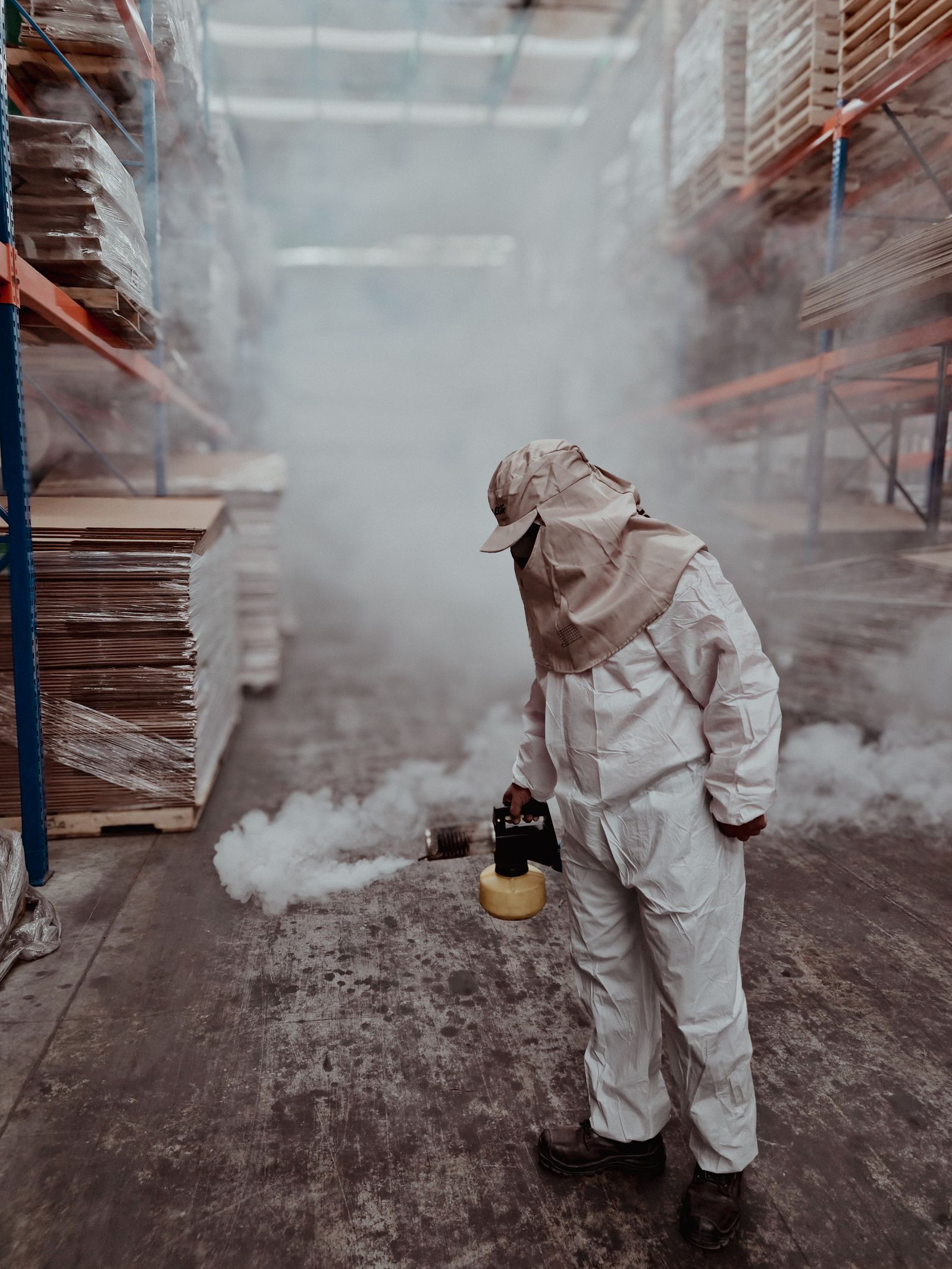A Lava Rock technician in protective coveralls treating a commercial warehouse interior